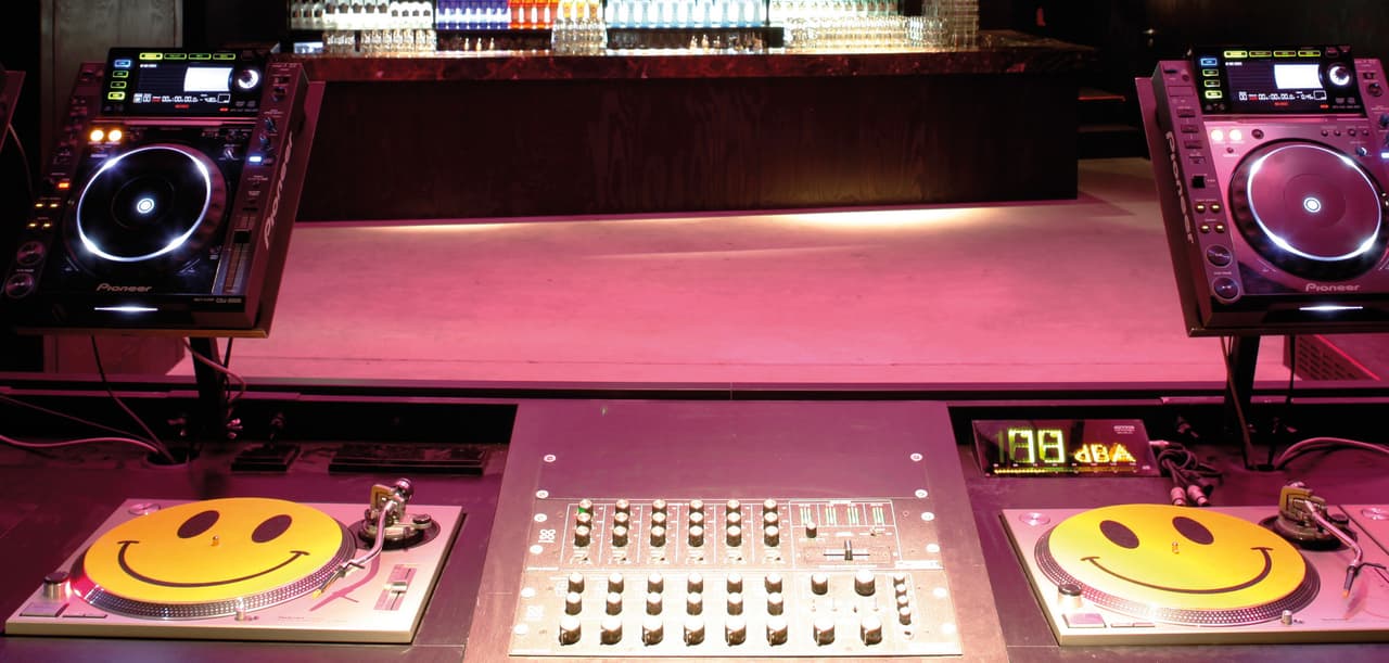 A club DJ booth with a mixer, two turntables and two CDJ players